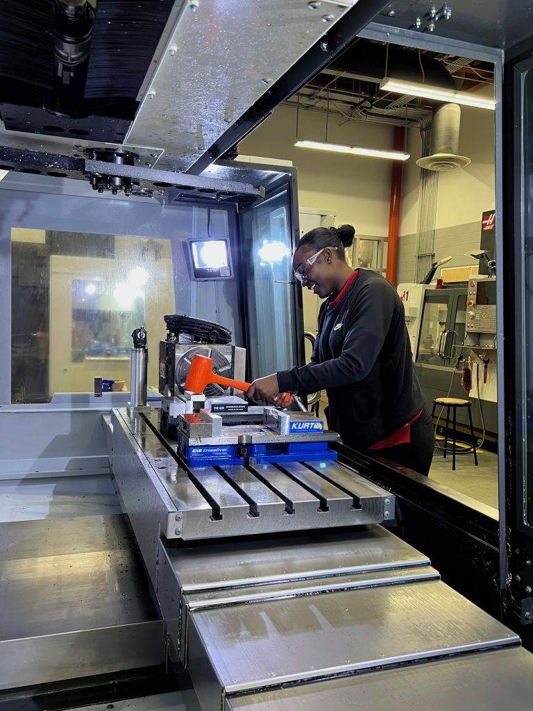 Mama Salla works inside a CNC machine during an Alamance Community College bootcamp.