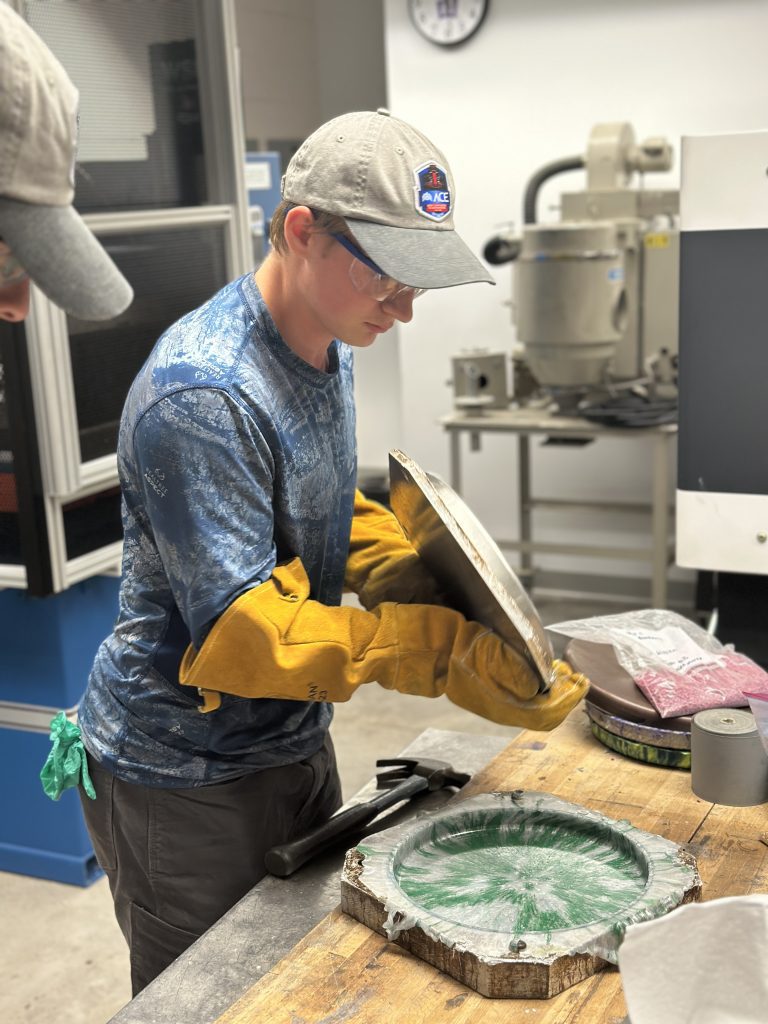 A student makes a compression molded part.